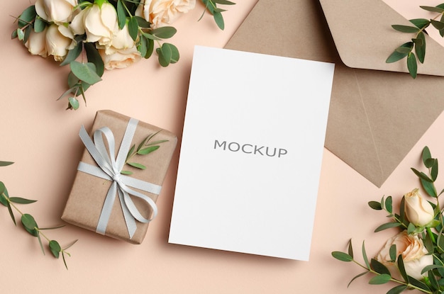 Mockup di biglietto di auguri in bianco con busta regalo e fiori di rose