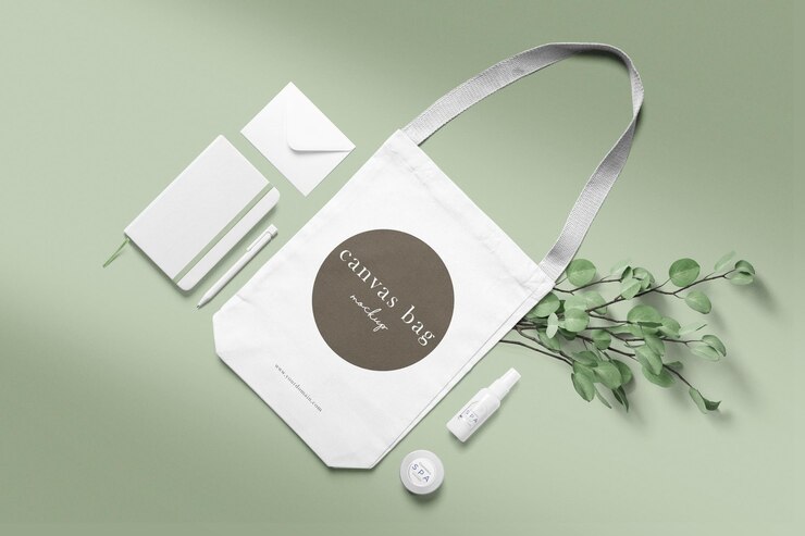 Mockup di borsa di tela minimale pulito su sfondo verde morbido con taccuino dispenser vaso e pianta di ramo
