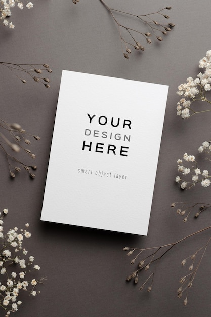 Mockup di carta di invito a nozze con ramoscelli di fiori secchi su grigio