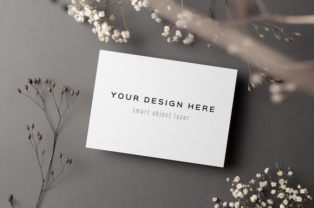 Mockup di carta di invito a nozze con ramoscelli di fiori secchi su grigio