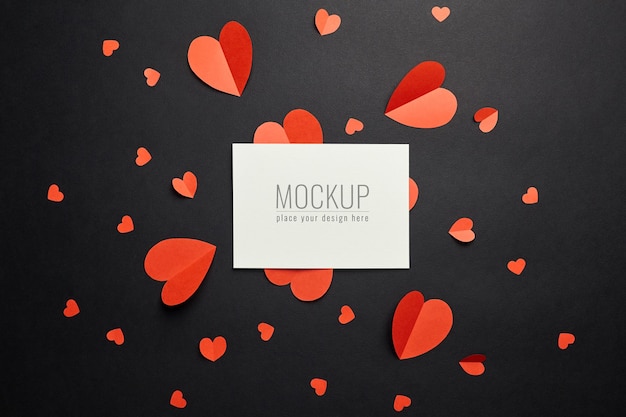 Mockup di carta di San Valentino con cuori di carta rossa su superficie nera