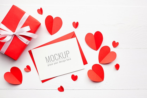 Mockup di carta di San Valentino con scatola regalo e cuori rossi su bianco