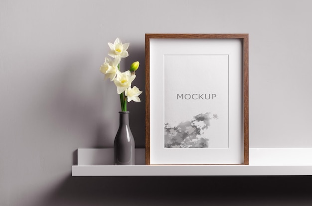 Mockup di cornice in legno su scaffale bianco con fiori di narcisi primaverili