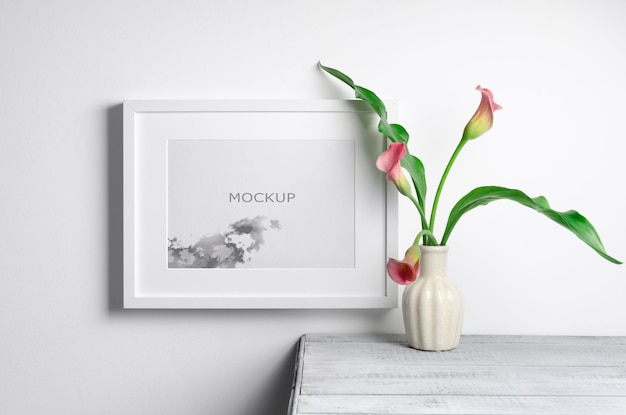 Mockup di cornice orizzontale con fiori di calla all'interno della stanza bianca