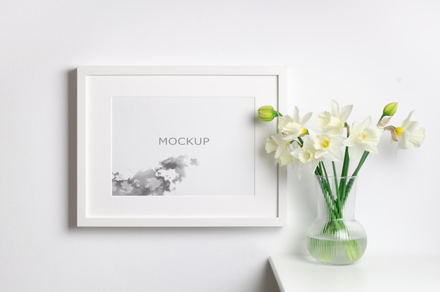 Mockup di cornice paesaggistica con fiori di narciso primaverile all'interno della stanza bianca