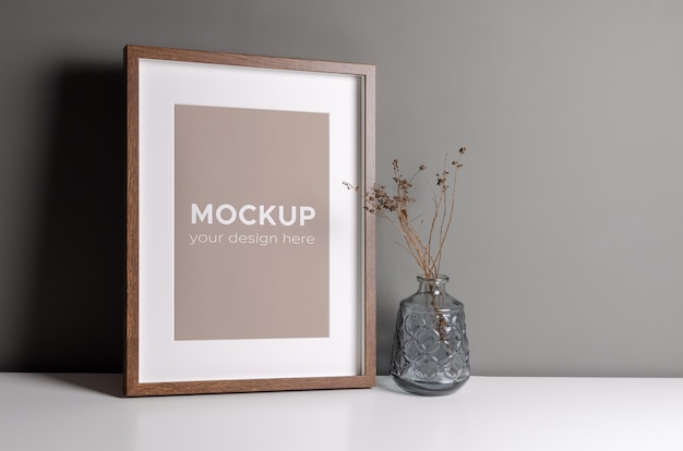 Mockup di cornice per foto su muro grigio con decorazioni di piante secche