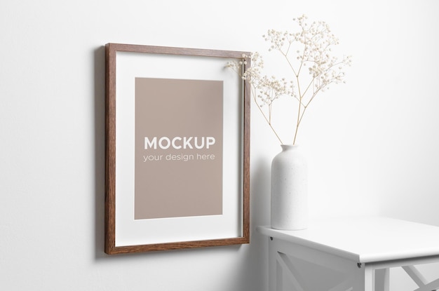 Mockup di cornice ritratto su parete bianca con decorazioni di fiori di gipsofila secca