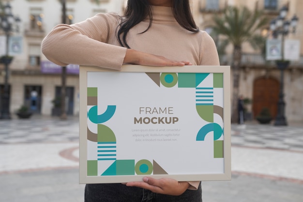 Mockup di cornice tenuto da una persona all'esterno