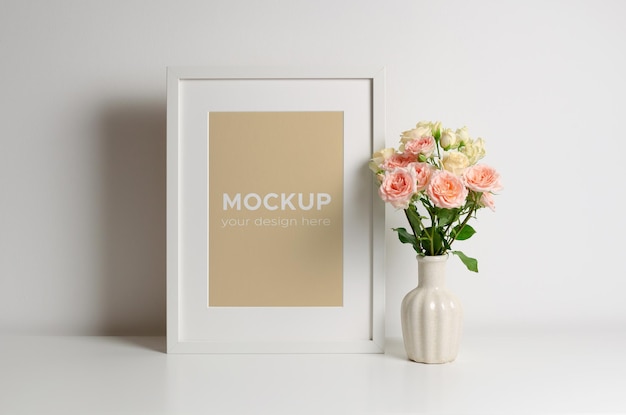 Mockup di cornice verticale in interni bianchi con bouquet di rose in vaso