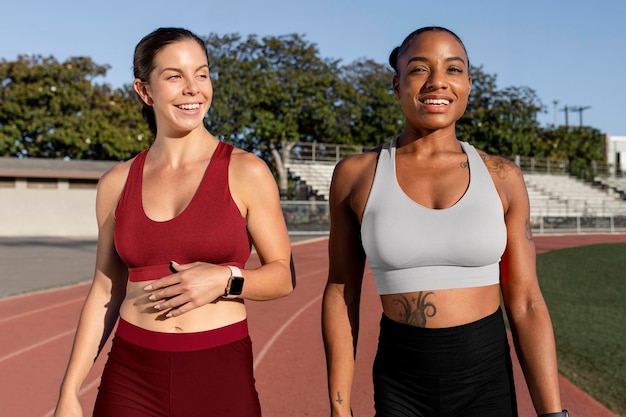 Mockup di reggiseno e pantaloncini sportivi psd su corridori atletici amici che parlano e camminano sulla pista