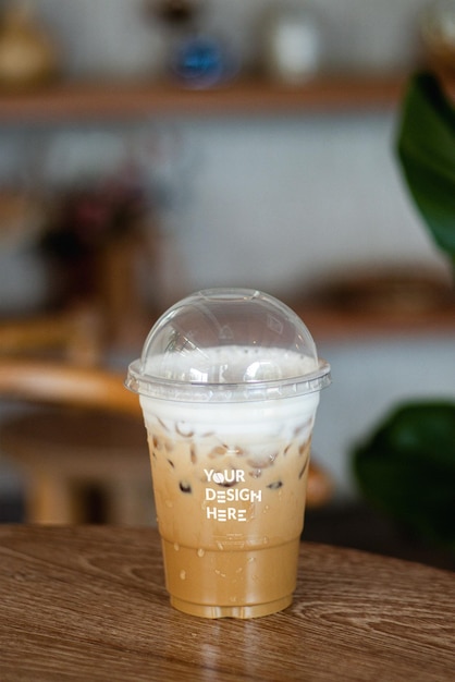 Mockup di una tazza di caffè usa e getta, caffè ghiacciato, cappuccino, latte mocha in tazza di plastica su un tavolo di legno