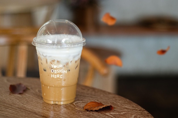Mockup di una tazza di caffè usa e getta, caffè ghiacciato, cappuccino, latte mocha in tazza di plastica su un tavolo di legno