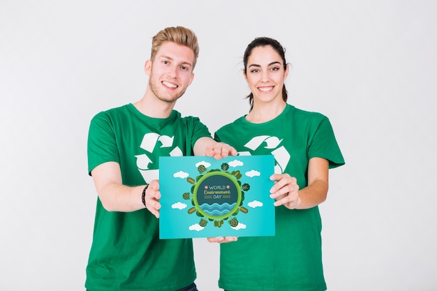 PSD mockup del día mundial del medio ambiente con pareja de voluntarios sujetando papel