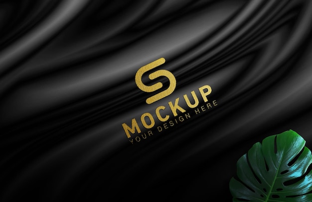 Mockup logo oro su tela nera con foglie