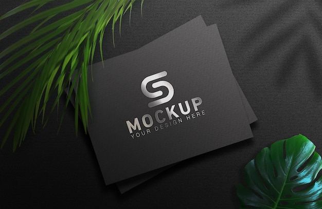 Mockup de logo plateado sobre papel negro con hojas