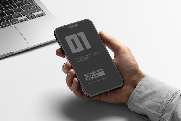 Un modèle de smartphone à la main sur une table de travail blanche