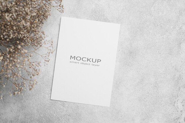 Modelo de invitación o tarjeta de felicitación en blanco con espacio para el texto colocado plano con flores secas y tarjeta