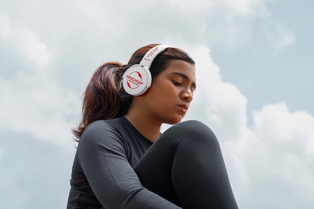 PSD mujer de ángulo bajo con auriculares al aire libre