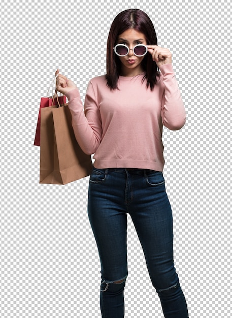 Mujer bonita joven alegre y sonriente, muy emocionada llevando una bolsa de compras, lista para ir de compras y buscar nuevas ofertas