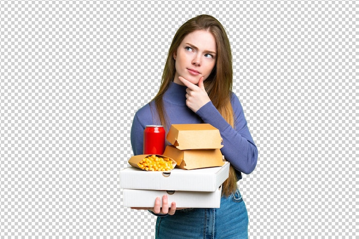 PSD mujer bonita joven sosteniendo pizzas y hamburguesas sobre un fondo clave de croma aislado que tiene dudas