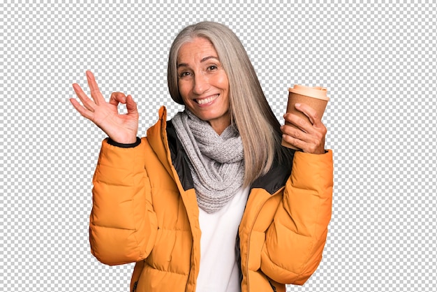 Mujer bonita senior de cabello gris con un anorak con un café caliente para llevar en invierno y un concepto frío