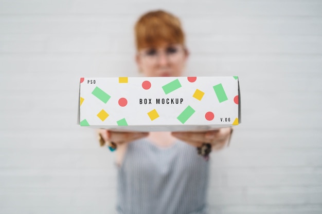 PSD mujer borrosa sujetando mockup de caja