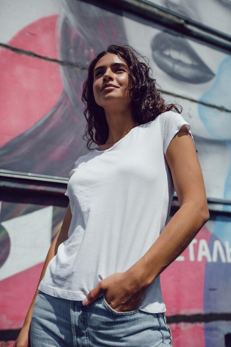 PSD mujer con camiseta blanca y pantalones cortos de denim posando frente a la pared de graffiti