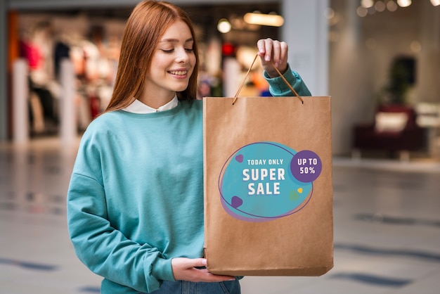 Mujer en un centro comercial con una gran bolsa de papel llena de productos a la venta