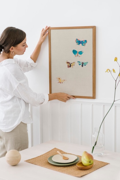 Mujer colgando un marco de fotos en una pared blanca