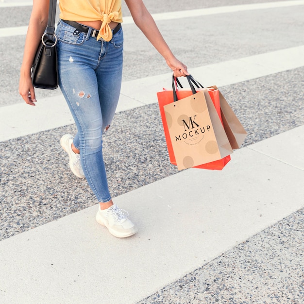 Mujer cruzando la calle y sosteniendo bolsas de la compra de maquetas