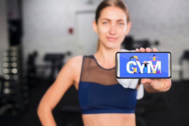 PSD mujer deportiva feliz presentando mockup de smartphone