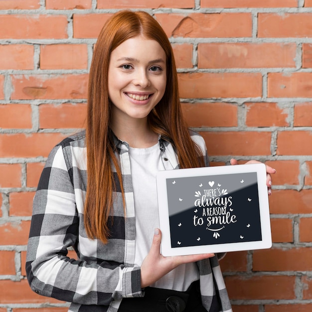 Mujer feliz que sostiene la maqueta de la tableta