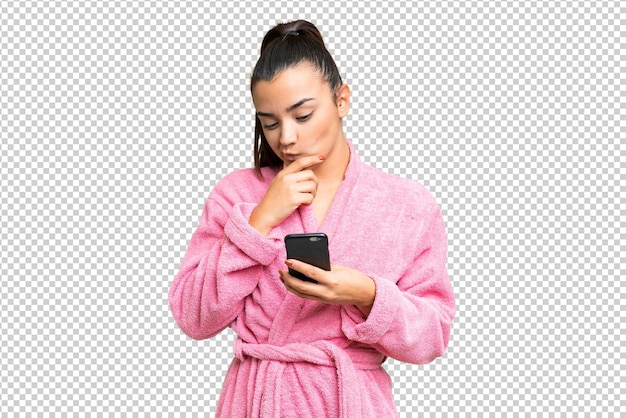 Mujer joven en una bata de baño sobre el fondo de la llave de croma aislada pensando y enviando un mensaje