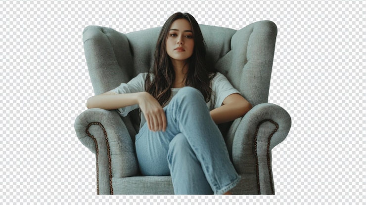 PSD una mujer joven de cabello largo sentada relajada en un acogedor sillón vestida casualmente con vaqueros y camiseta durante un momento tranquilo en el interior