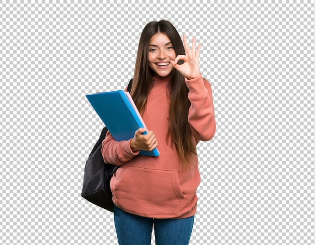 Mujer joven estudiante sosteniendo cuadernos mostrando signo bien con los dedos