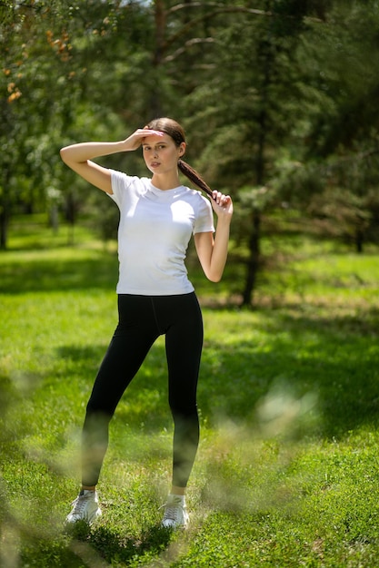 Mujer joven en ropa deportiva posando al aire libre en un parque en un día soleado
