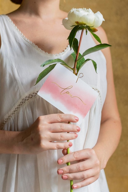 Mujer con una maqueta de tarjeta y flor de snowboard paeonia blanca