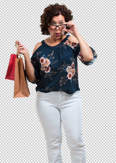 PSD mujer de mediana edad alegre y sonriente, muy emocionada llevando una bolsa de compras, lista para ir de compras y buscar nuevas ofertas.