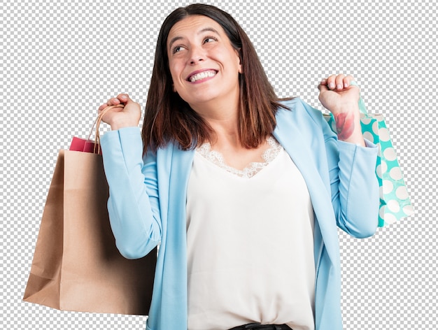 PSD mujer de mediana edad, alegre y sonriente, muy emocionada llevando bolsas de la compra.