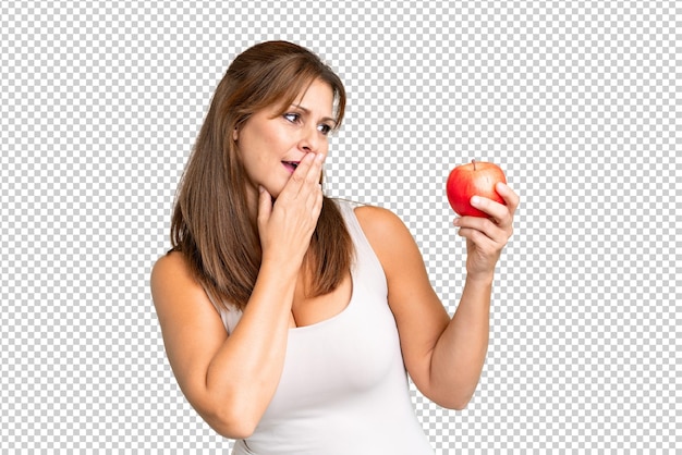 Mujer de mediana edad con una manzana sobre un fondo aislado con sorpresa y expresión facial conmocionada