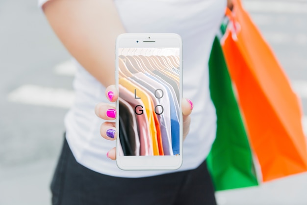 Mujer con mockup de smartphone y bolsas de compra