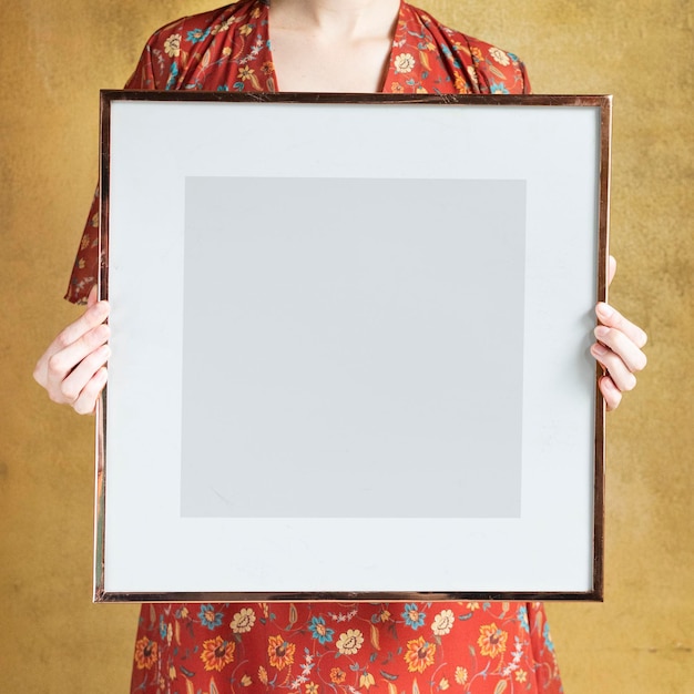 Mujer mostrando una maqueta de marco de fotos en blanco