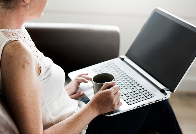 mujer que usa la computadora portátil en el sofá