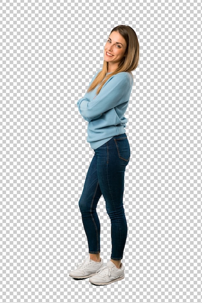 Mujer rubia con camisa azul que mantiene los brazos cruzados en posición lateral mientras sonríe.