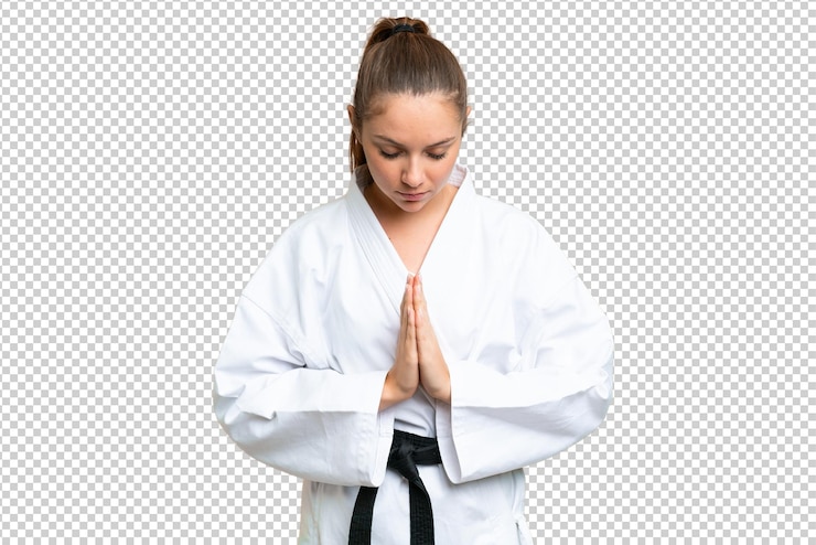 PSD mujer rubia joven sobre fondo clave de croma aislado haciendo karate y saludando