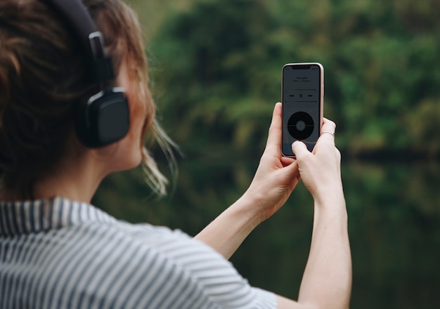 Mujer sola en la naturaleza escuchando música con auriculares