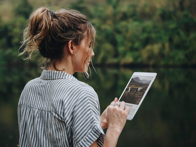 Mujer sola en la naturaleza con una tableta digital conexión a internet y concepto de viaje
