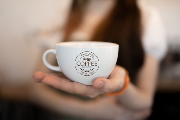 Mujer sosteniendo maqueta de taza de café