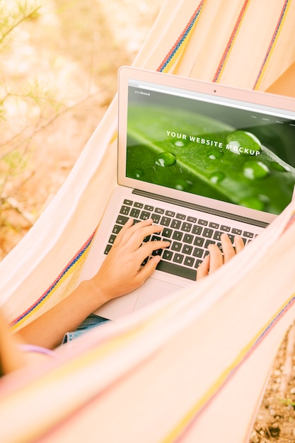 Mujer usando mockup de portátil en la naturaleza