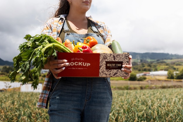 Mujer vista frontal sosteniendo una caja en la naturaleza